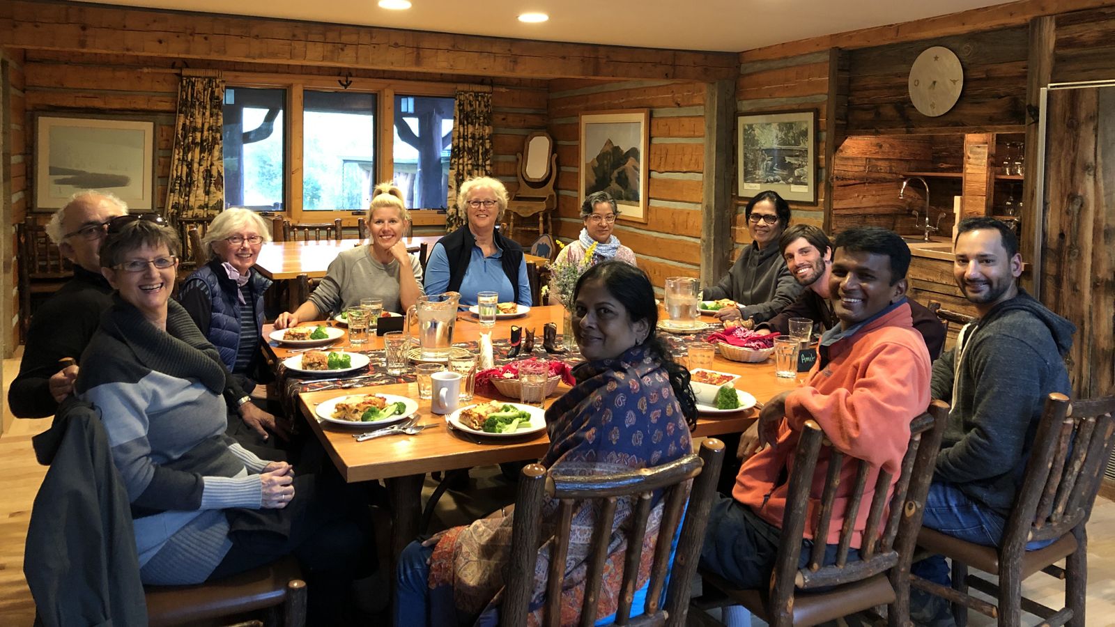 Smiling guests gathered around a dinner table in a wood-paneled lodge